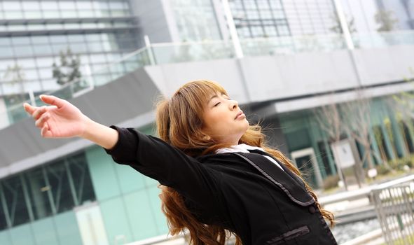 Woman relaxing with arms open enjoying her freedom and office building background