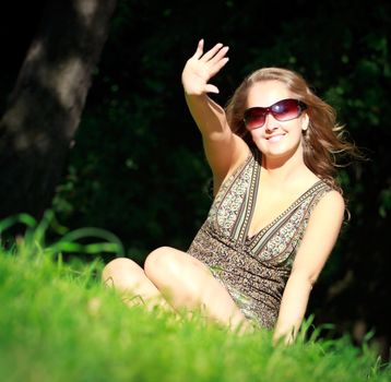 beautiful girl in sunglasses sitting in grass