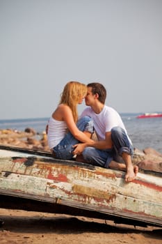young couple sitting on old boat and kiss