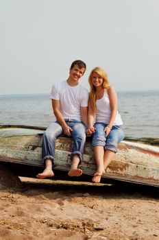 beautiful couple on a beach sitting on old boat