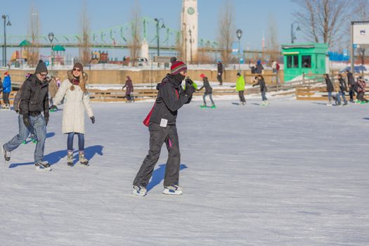 A lonely woman is ice skating alone around all the other people in the Skating Rink in Old Port of Montreal, Quebec , Canada