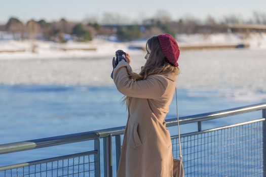 A random woman taking a picture of Saint Lawrence river in cold winter day in Montreal, Quebec, Montreal
