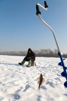 The fisherman on winter fishing in frosty day