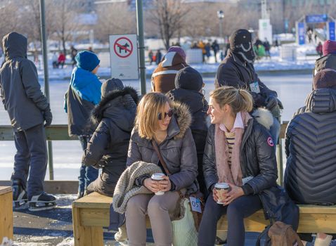 A woman trying to wear her winter gloves with her coffee in a cold winter day in the Skating Rink in Old Port of Montreal, Quebec ,Canada