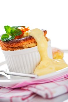 Cointreau or whiskey soufflé with orange, mint and vanilla sauce on white background