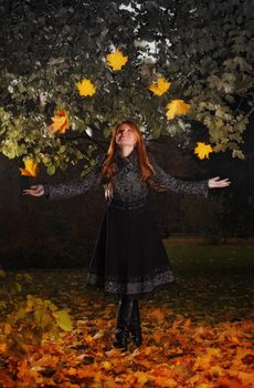 beautiful girl juggling leaves in autumn park
