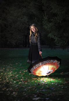 girl with umbrella in autumn park at evening