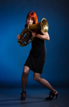girl in black dress with trumpet, blue background