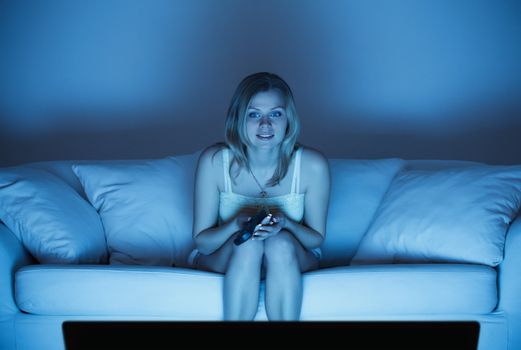beautiful lonely woman sitting on couch and watching tv