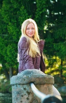 beautiful blond woman standing near concrete fence