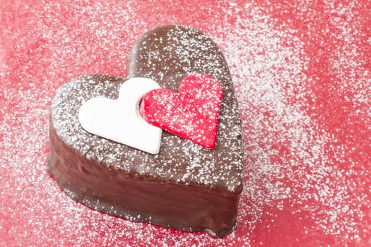 Heart shaped slice of a chocolate-cake on red background