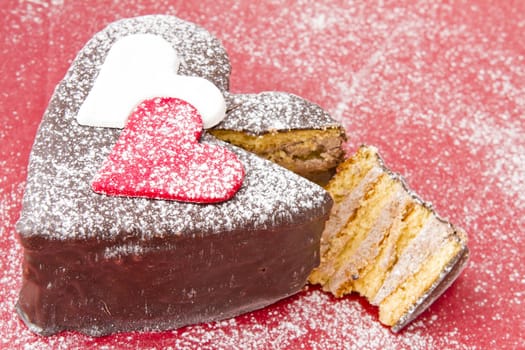 Heart shaped slice of a chocolate-cake on red  plate