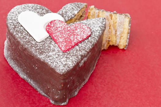 Heart shaped slice of a chocolate-cake on red  table