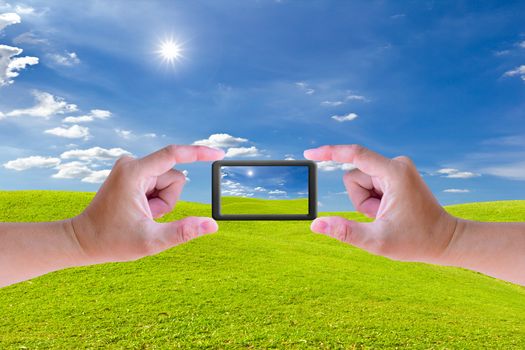 hand holding mobile phone and green grass meadow