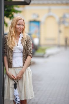 beautiful girl with umbrella near bus stop at rainy day