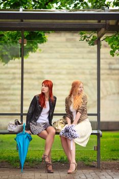 two girls at bus stop, rainy day