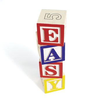 Four wooden alphabet blocks on white background, stacked to form the word, 'easy'. Stack of blocks casts a shadow.