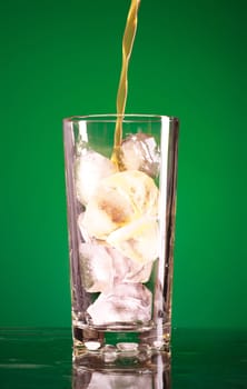 pouring soda in glass over green background