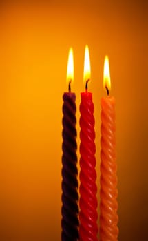 three twisted burning candles over yellow background