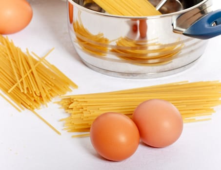 spaghetti, eggs and kitchen utensil on table