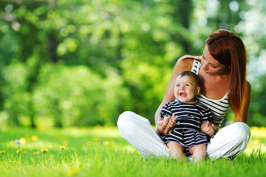 Happy mother and daughter on the green grass