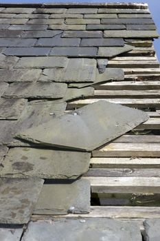 broken and fallen slate leaves holes in a roof due to storm or decay