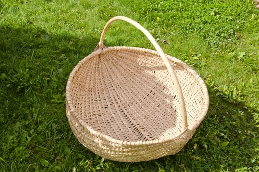 Wicker basket handmade on green grass. Village industrial object.