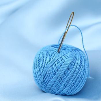 thread on blue silk background close up