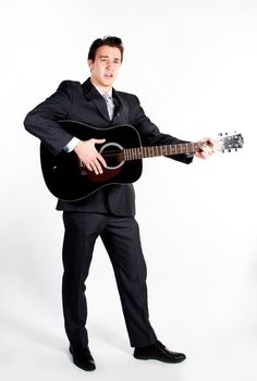 Young handsome man in a dark business suit, sings and plays guitar
