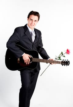 Young handsome man in a dark business suit, sings and plays guitar