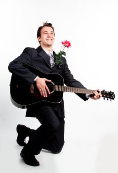 Young handsome man in a dark business suit, sings and plays guitar