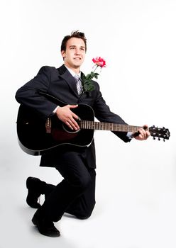 Young handsome man in a dark business suit, sings and plays guitar