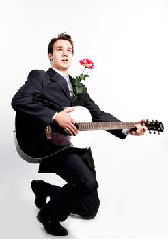 Young handsome man in a dark business suit, sings and plays guitar