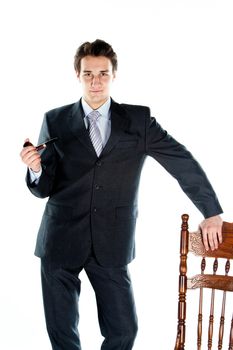 Portrait of a young handsome man in a dark suit with a strict smoking a pipe in his hand