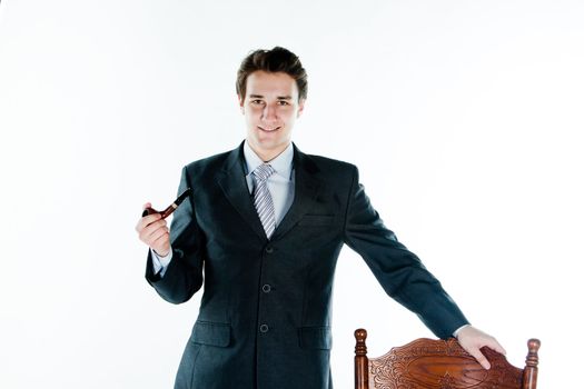 Portrait of a young handsome man in a dark suit with a strict smoking a pipe in his hand