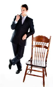 Portrait of a young handsome man in a dark suit with a strict smoking a pipe in his hand