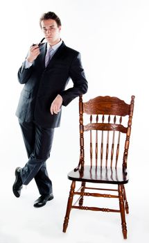 Portrait of a young handsome man in a dark suit with a strict smoking a pipe in his hand