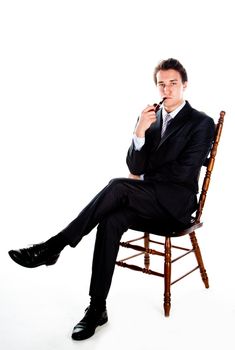 Portrait of a young handsome man in a dark suit with a strict smoking a pipe in his hand
