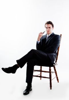 Portrait of a young handsome man in a dark suit with a strict smoking a pipe in his hand