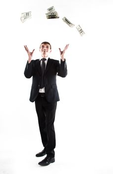 Portrait of a young businessman in a dark suit surrounded by flying dollar bills