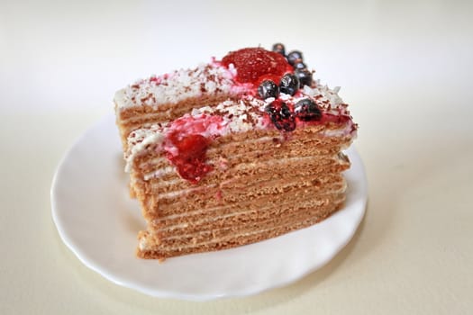 delicious honey puff cake on a plate decorated with strawberries, blueberries and grated chocolate