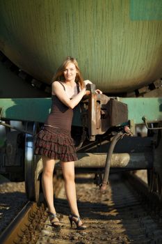 beautiful girl standing on rails near railroad car