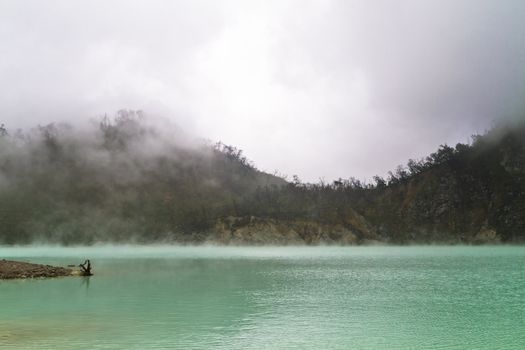 volcanic crater lake of Kawah Putih Bandung Indonesia with green coor water and fog
