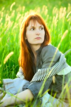 sad woman sitting in field at summer day