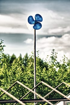 blue garden windmill against cloudy sky at summer day