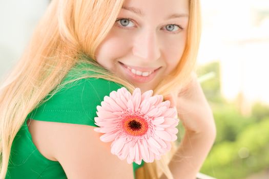 beautiful blond girl with pink gerbera flower, close up