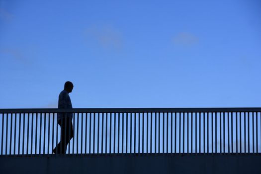 Silhouette of a walking man on a bridge