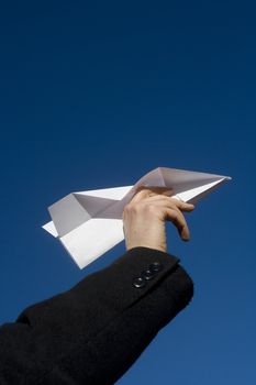 Hand holding a Paper Airplane towards blue sky