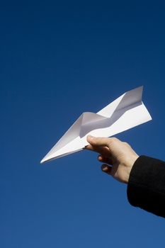 Hand holding a Paper Airplane towards blue sky