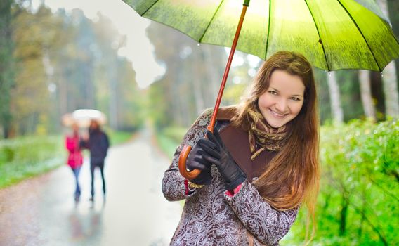 laughing girl and walking couple under rainfall in autumn park